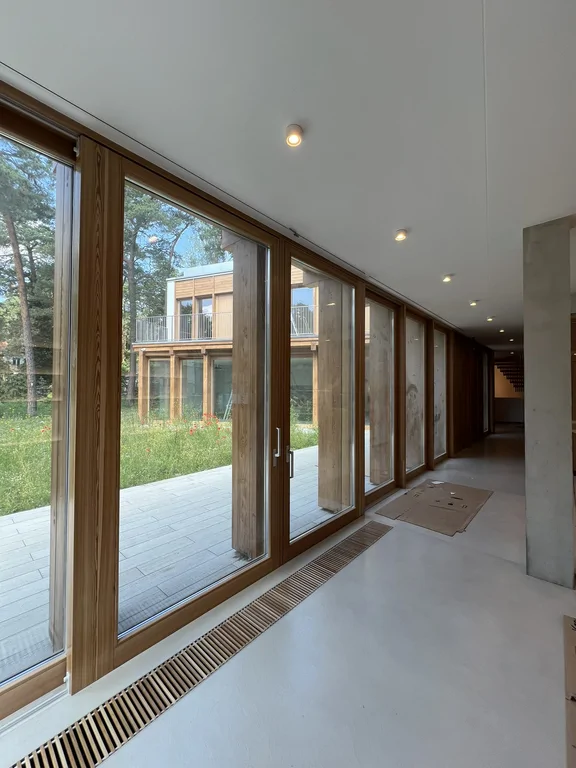 Korytarz z dużymi drewnianymi przeszkleniami i widokiem na wewnętrzny dziedziniec