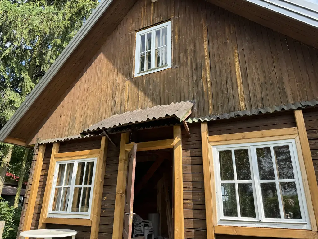 Domek drewniany przed remontem – front i boczna elewacja z otwartymi drzwiami.