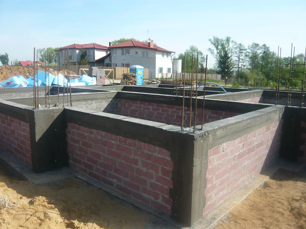 Wzniesione ściany fundamentowe z bloczków, wykonany wieniec i wystające zbrojenie pod słupy