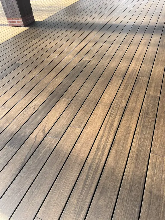 Zbliżenie nawierzchni tarasu po remoncie z ułożeniem drewnopodobnych desek i cienkimi fugami.