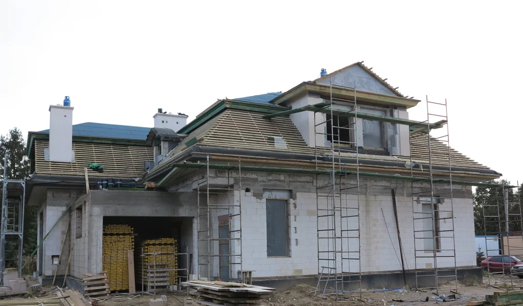 Stan surowy budowy domu jednorodzinnego, więźba dachowa, kominy, rusztowania 