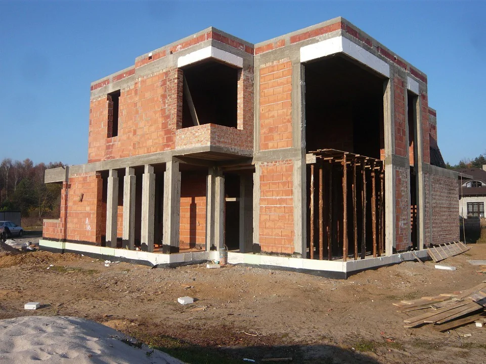 Elewacja w stanie surowym z podcieniem – słupy żelbetowe i duże otwory przeszklenia