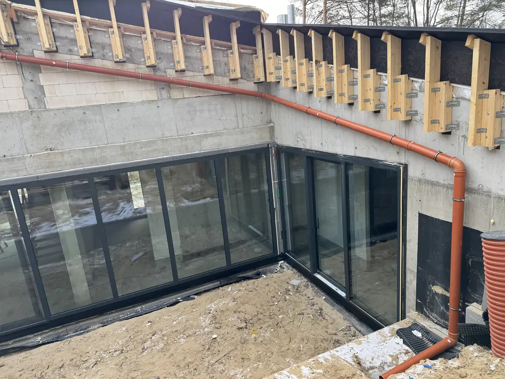Detal bocznej ściany żelbetowej z izolacją przeciwwodną i instalacją odwodnienia dachu.