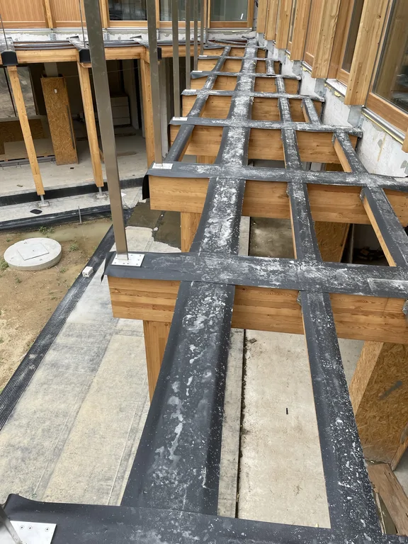 Widok z góry na drewnianą pergolę tarasową przygotowaną pod dalsze warstwy wykończeniowe