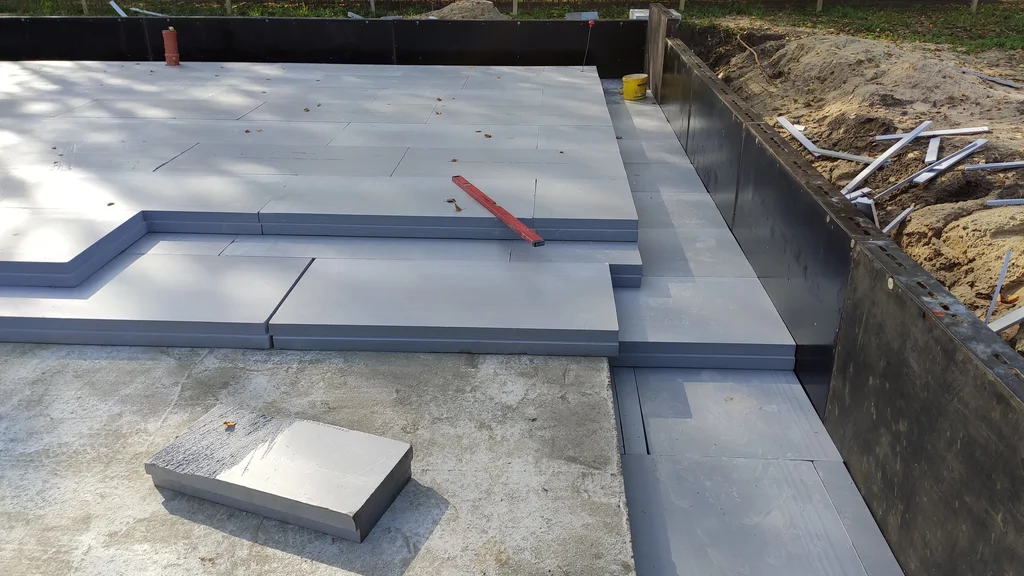 Układanie płyt termoizolacyjnych XPS na chudziaku płyty fundamentowej – przygotowanie warstw pod dalsze prace.