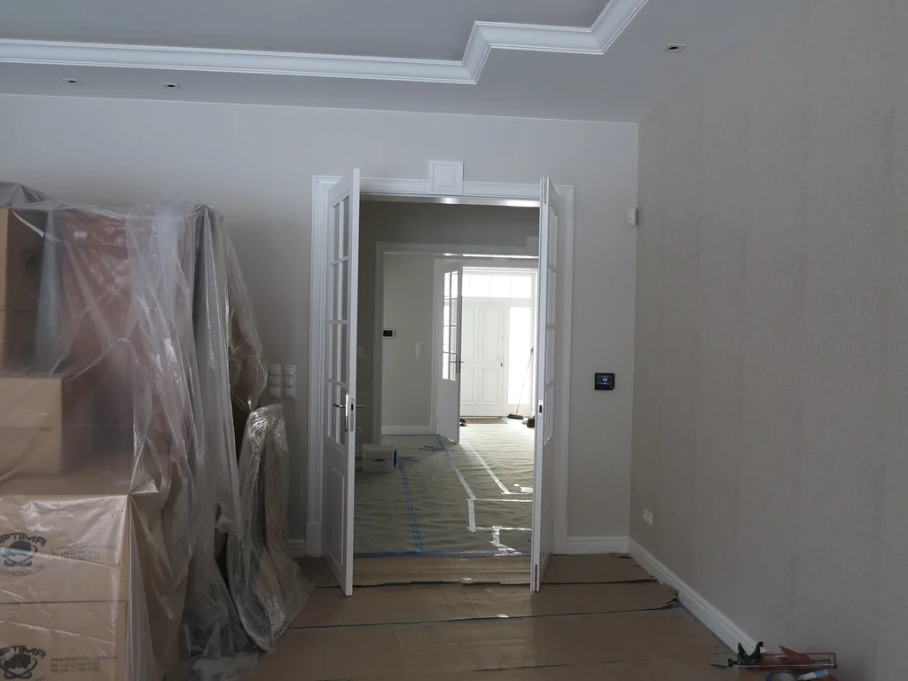 kuchnia w stylu dworkowym, z jasną stolarką okienną i meblami, w kuchni ciemny blat z kamienia 