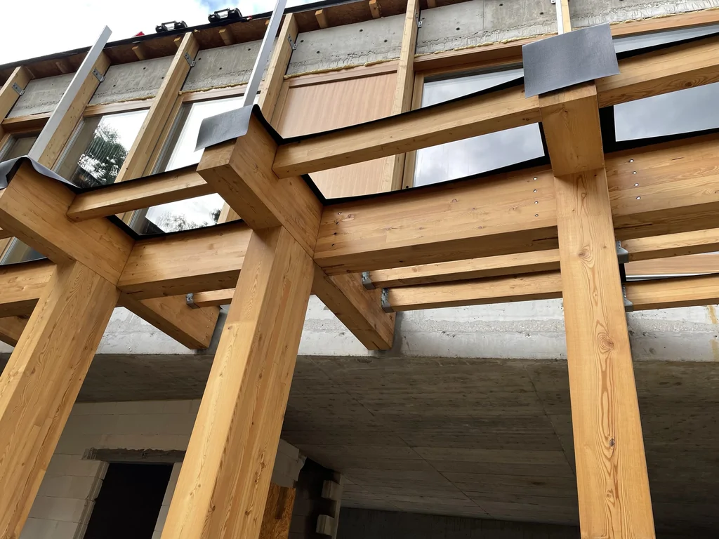 Detal drewnianej pergoli i dużych przeszkleń elewacji w nowoczesnym domu jednorodzinnym podczas budowy