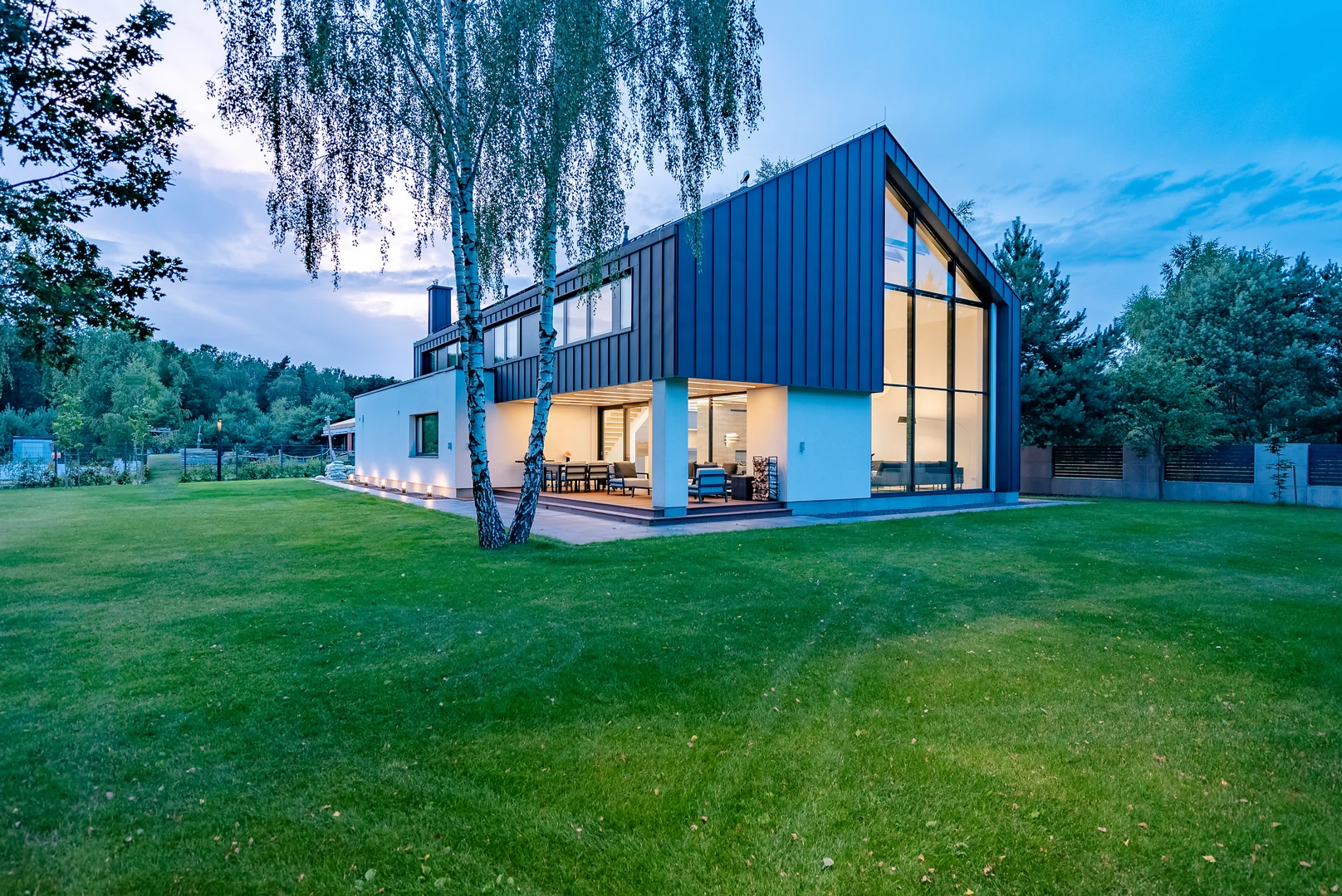 Nowoczesny dom jednorodzinny z dużymi przeszkleniami i tarasem – budowa domu przez firmę budowlaną