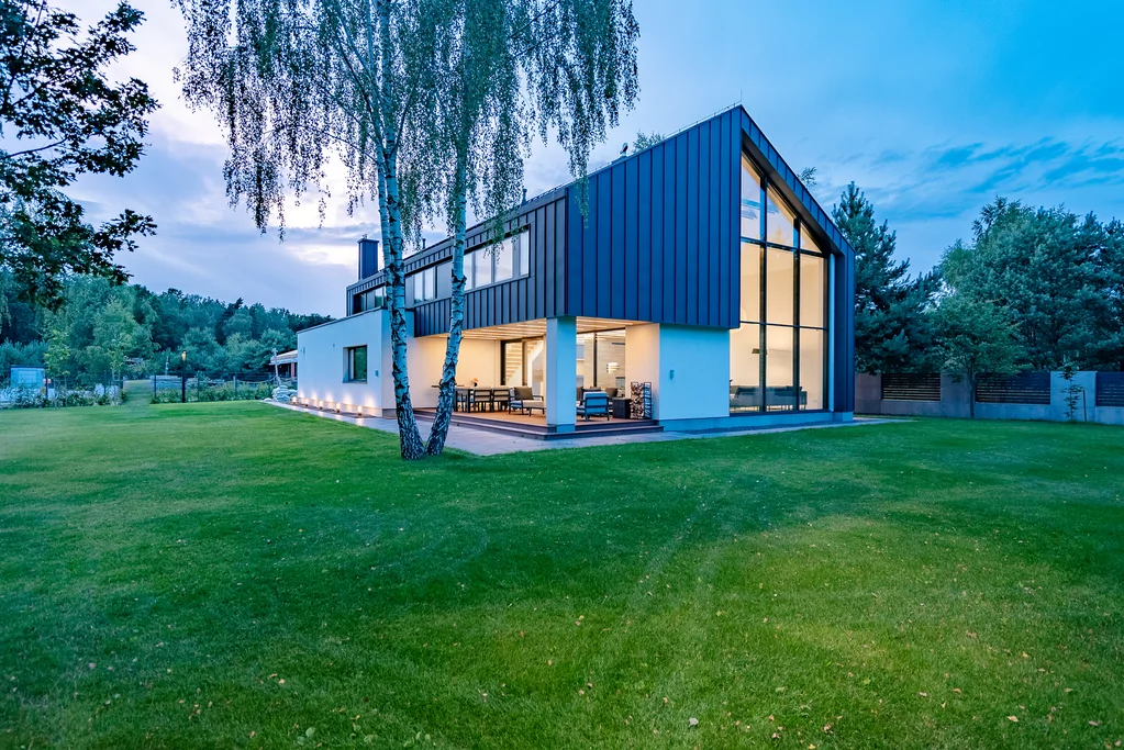 Nowoczesny dom jednorodzinny z dużymi przeszkleniami i tarasem – budowa domu przez firmę budowlaną