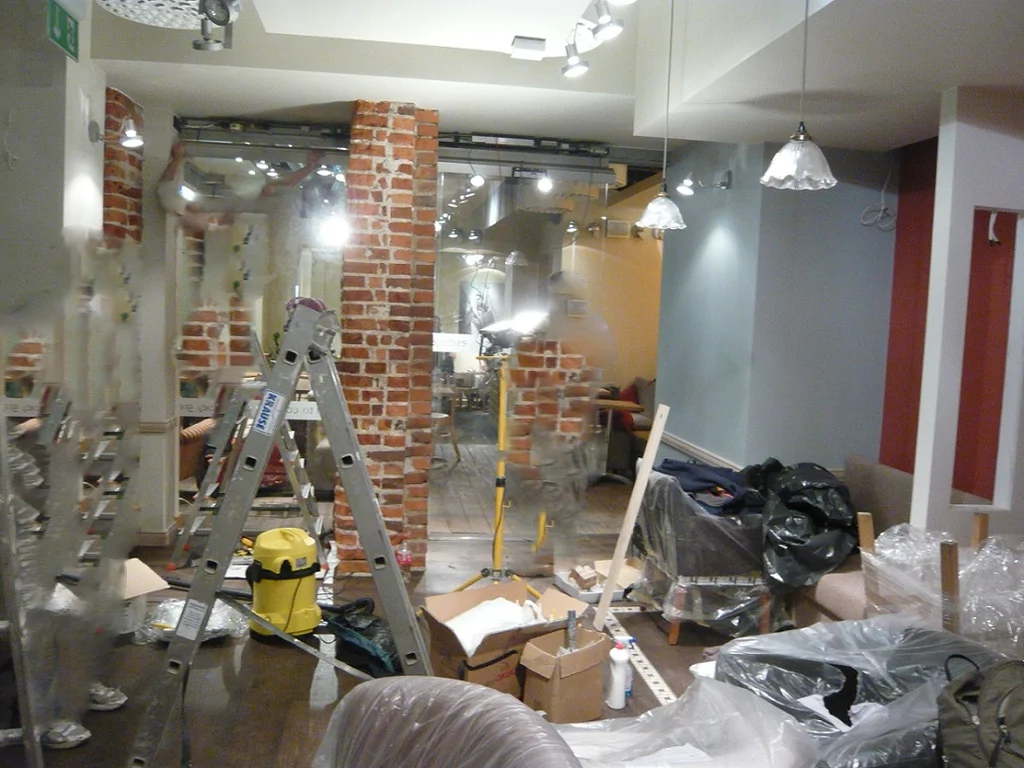 Etap wykończeń w Green Caffè Nero, drabina i materiały budowlane przy ceglanych filarach