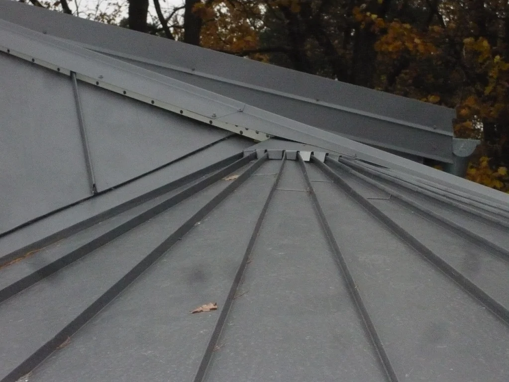 Zbliżenie na dach z blachy na rąbek stojący; linie rąbków i obróbki przy krawędzi.