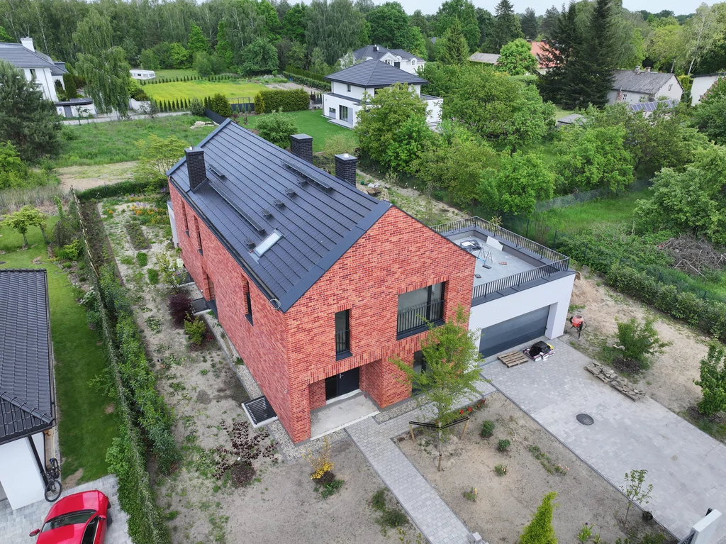 Widok z góry na front domu z dachem dwuspadowym, garażem i ścieżką prowadzącą do wejścia