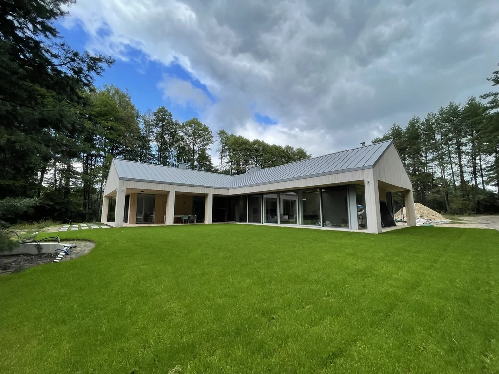 Widok ogólny domu z zielonym trawnikiem i zadaszonym tarasem