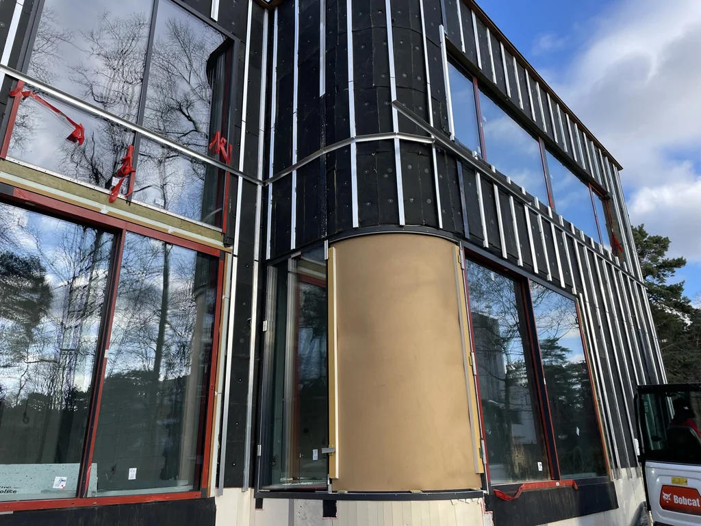 Szeroki widok nowoczesnego domu o geometrycznej bryle z ciemną elewacją i dużymi przeszkleniami