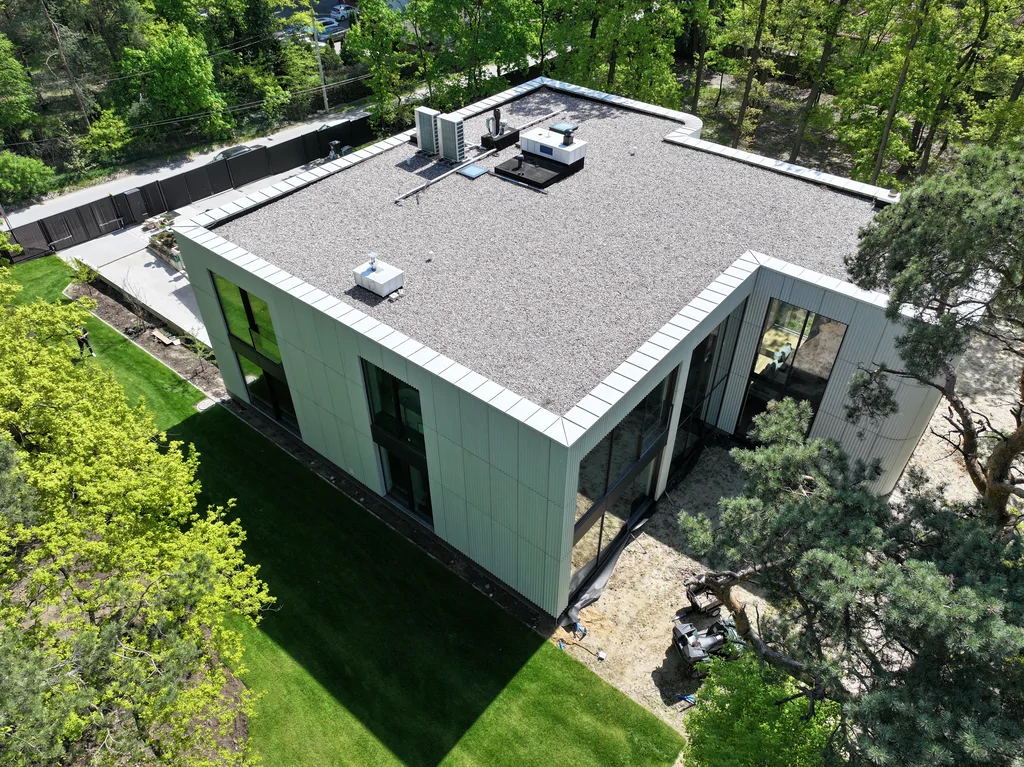 Boczno-tylna elewacja domu z wysokimi oknami na dwie kondygnacje i jasną ryflowaną okładziną