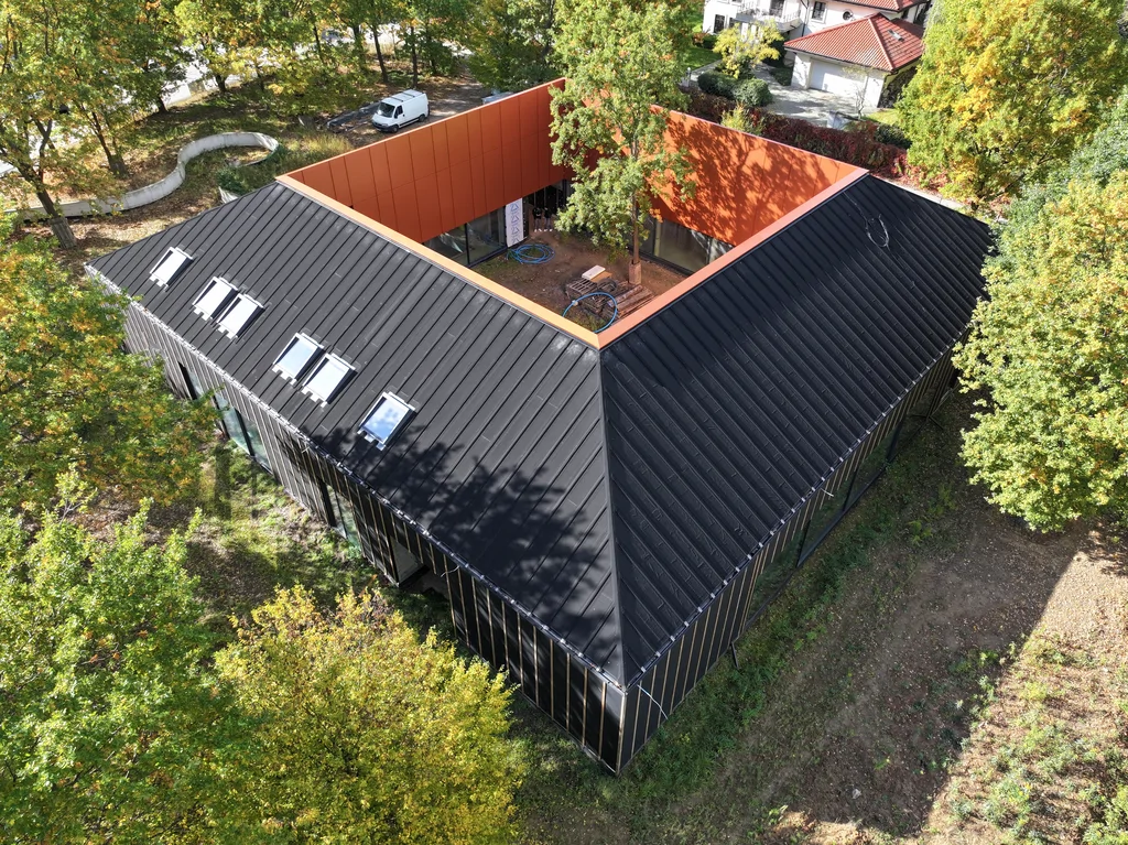 Czarna bryła domu z centralnym patio i drzewem pośrodku