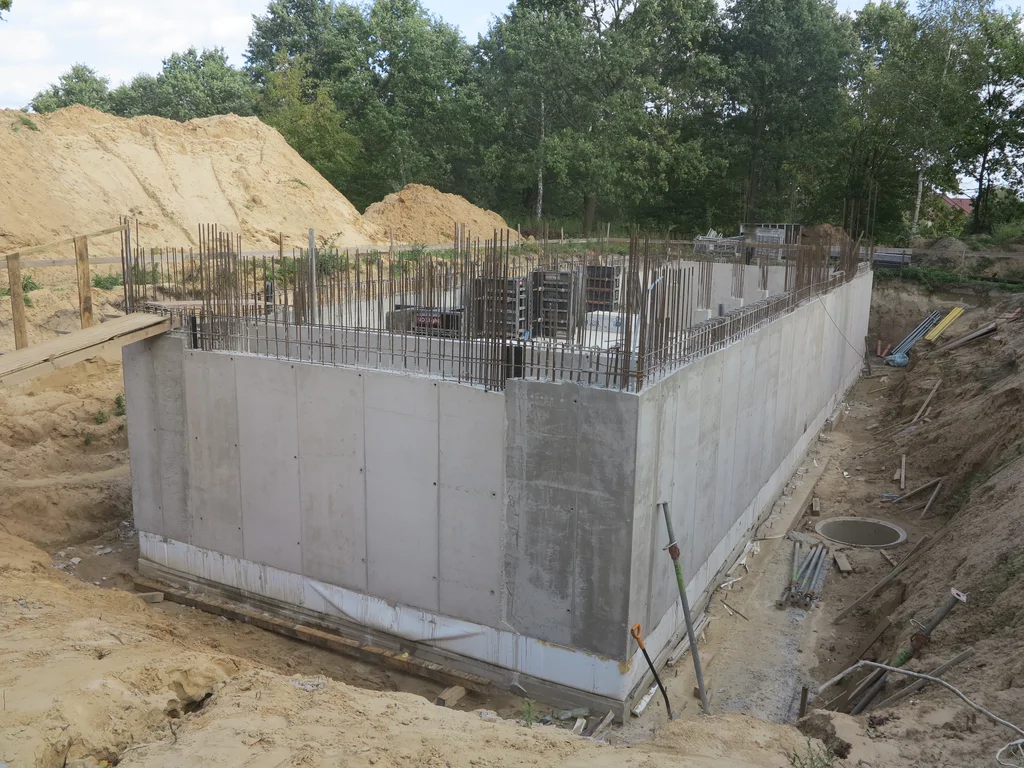 Wylane ściany żelbetowe piwnicy w technologii białej wanny w wykopie z wypuszczonym zbrojeniem – baza pod parter i piętro z betonu architektonicznego