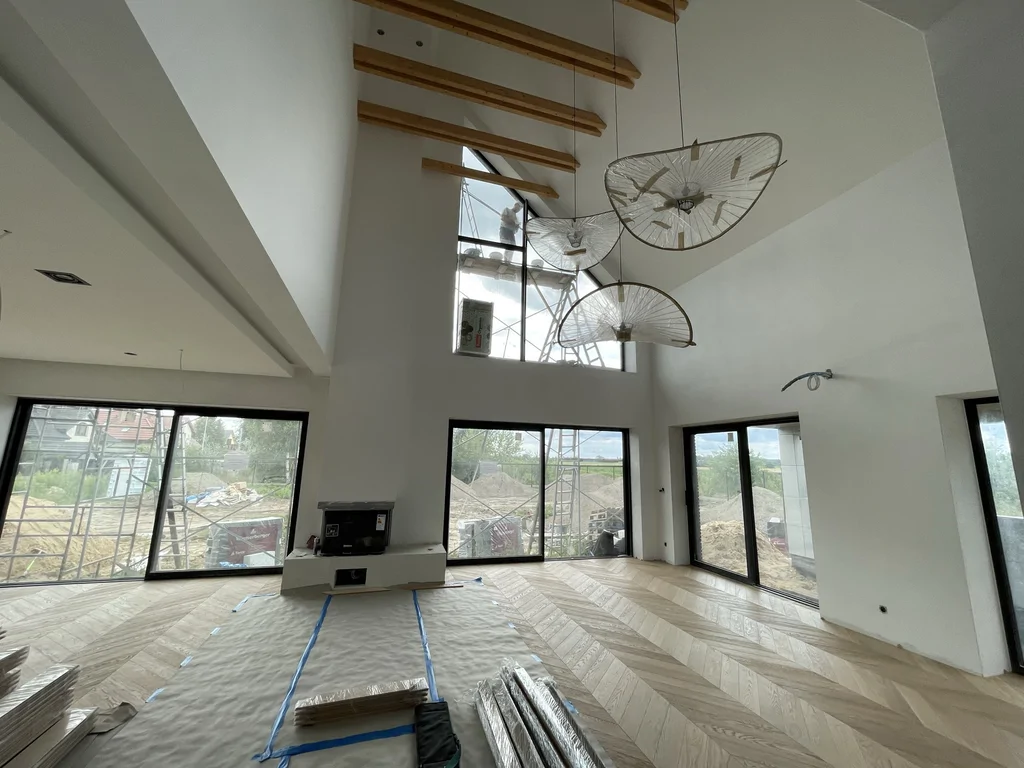 Wnętrze salonu dwukondygnacyjnego – przeszklenia, kominek, podłoga w jodełkę