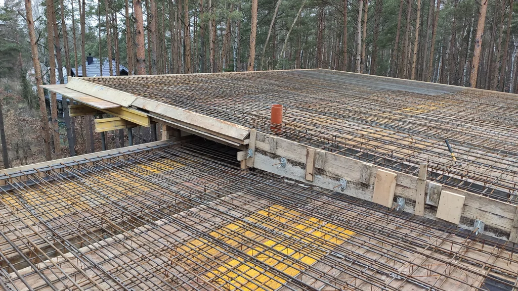 Detal zbrojenia stropu z krawędziowym szalunkiem i przepustem instalacyjnym w płycie