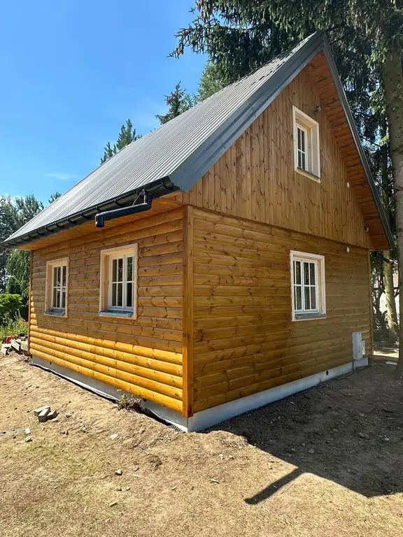 Boczna elewacja drewnianego domku po renowacji – zbliżenie nowego wykończenia.