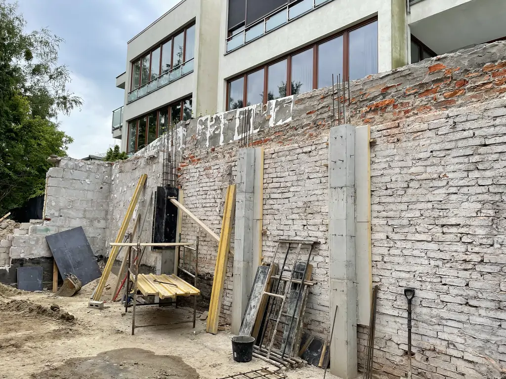 Wzmacnianie istniejącej ściany murowanej żelbetowymi słupami podczas prac konstrukcyjnych.