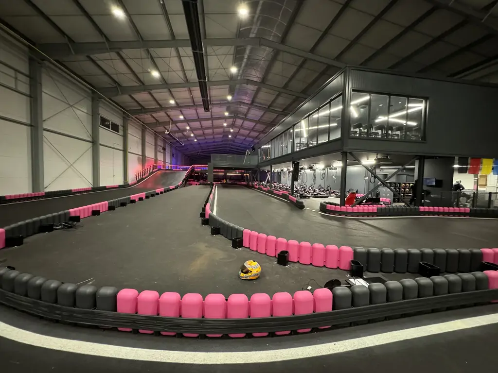 Szeroki widok na gotowy tor gokartowy z antresolą, zakrętami i oświetleniem LED w nowoczesnej hali.