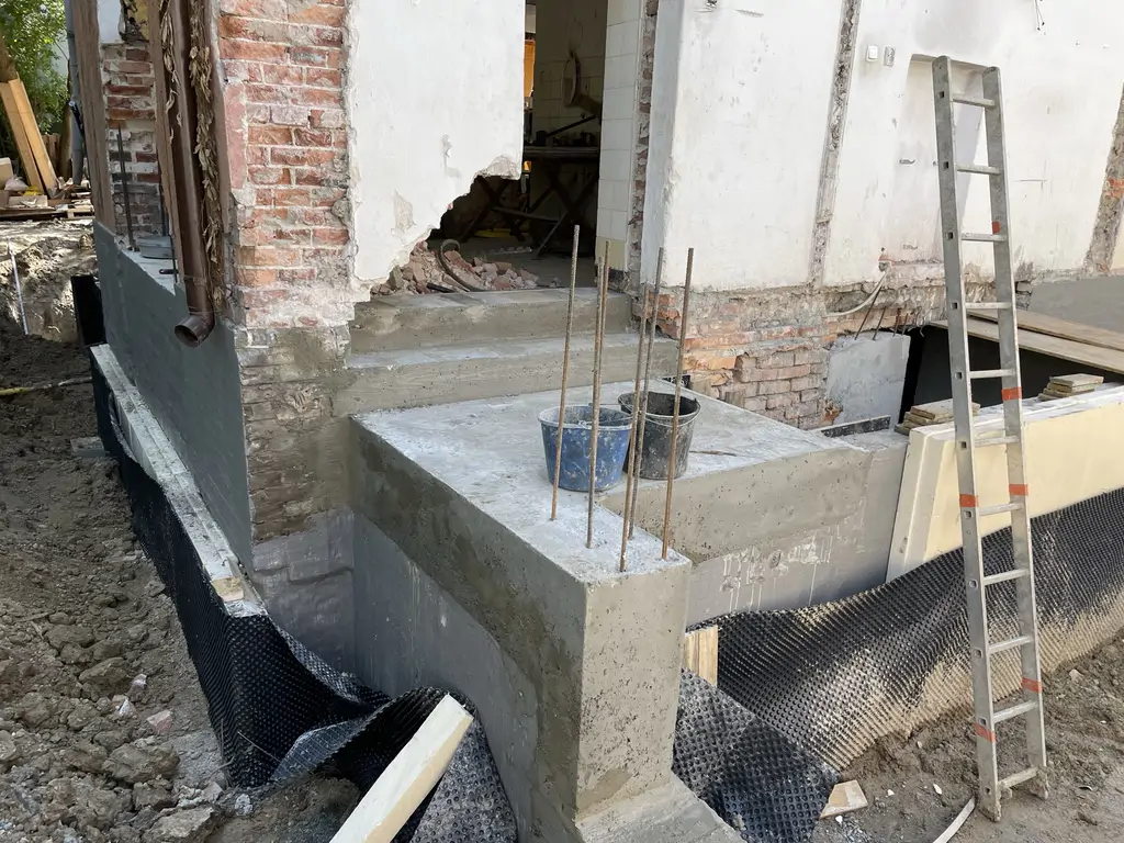 Nowe schody i izolacja fundamentów wykonywane podczas remontu zewnętrznej części budynku.