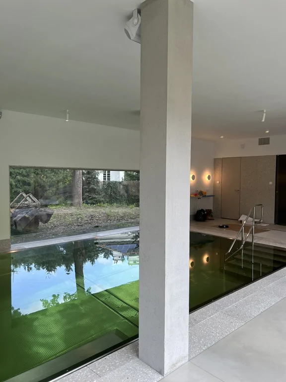 Wewnętrzny basen z dużym przeszkleniem, betonowym słupem i minimalistycznym wykończeniem
