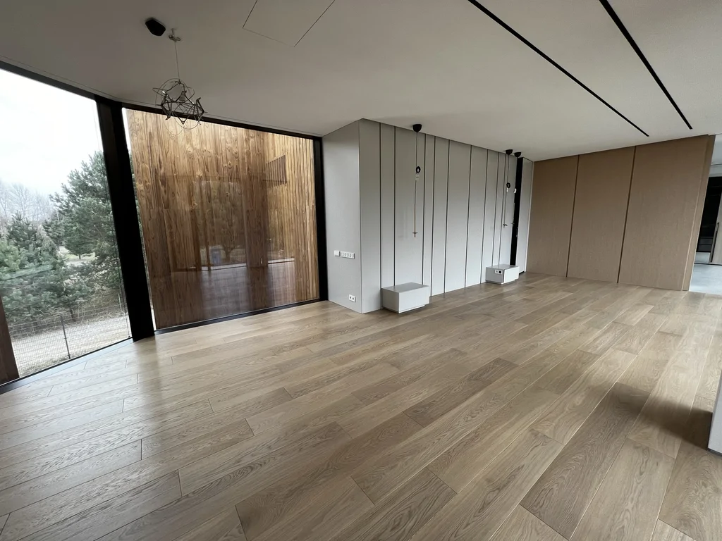 Duża kubatura, dębowa podłoga i zabudowy ścienne w minimalistycznej formie. Światło dzienne jako główny “dekor”.