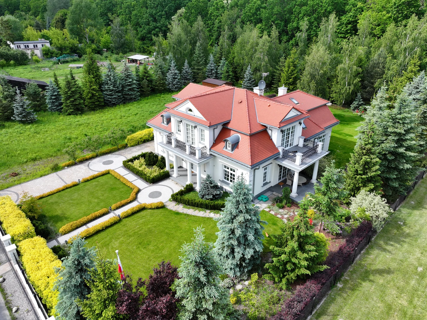 Luksusowa willa z klasyczną bryłą, czerwonym dachem i reprezentacyjnym ogrodem – budowa domów premium