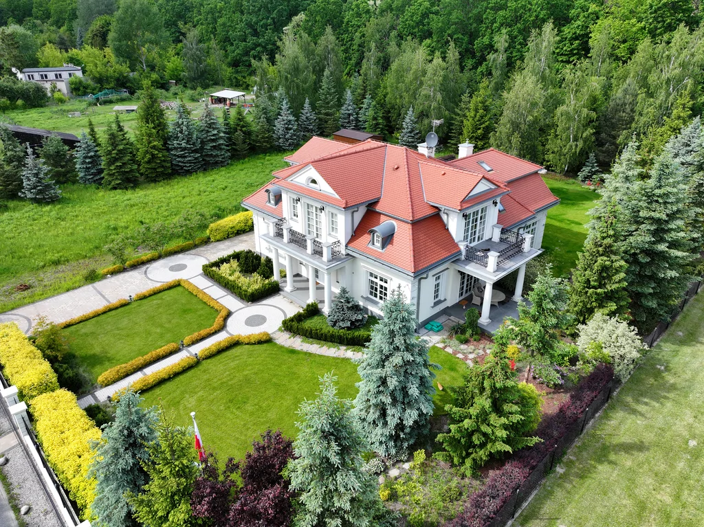 Luksusowa willa z klasyczną bryłą, czerwonym dachem i reprezentacyjnym ogrodem – budowa domów premium