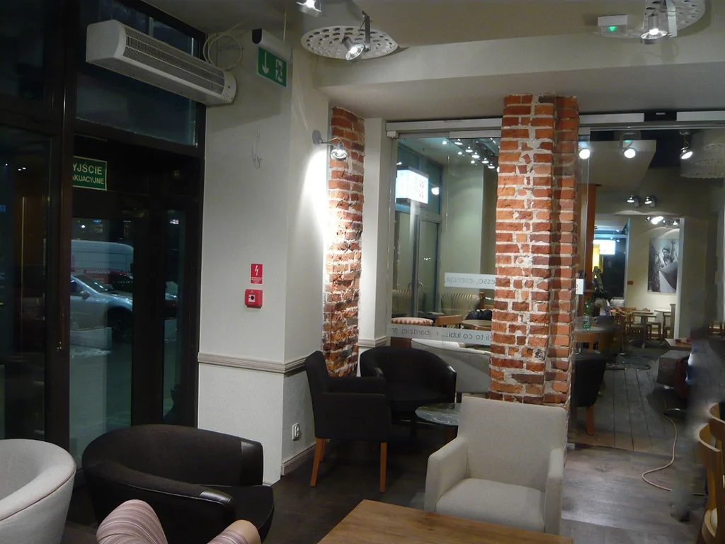 Wnętrze Green Caffè Nero po remoncie, ceglane filary przy witrynie i strefa foteli
