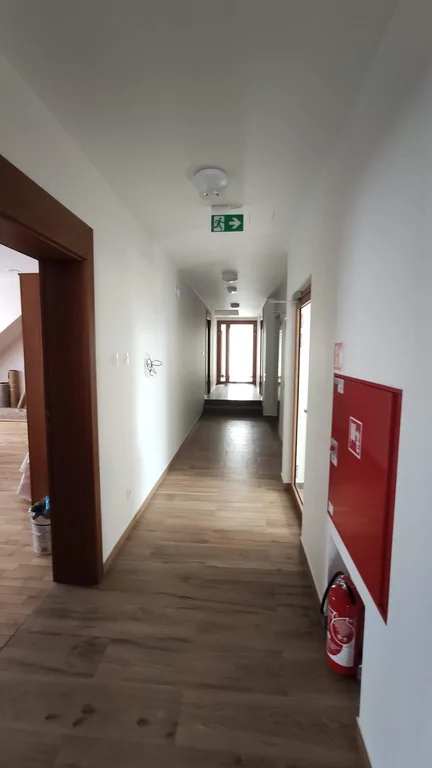 widok na korytarz, podłoga z paneli, drewniane framugi drzwi jasne ściany 