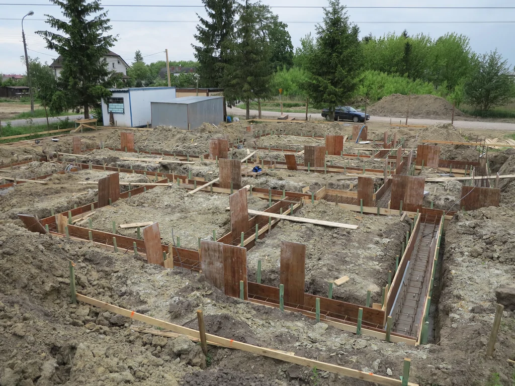 Wykop, fundamenty na ławach w tle widoczny szalunek oraz zbrojenie ław fundamentowych 