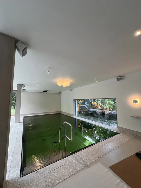 Wewnętrzny basen z wejściem po schodach i poziomym oknem wychodzącym na ogród