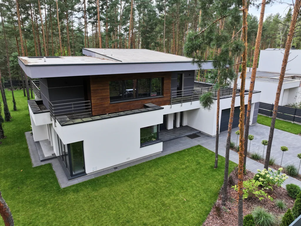 Zbliżenie z drona na elewację: drewniana okładzina na piętrze, stalowe balustrady i podcień przy wejściu