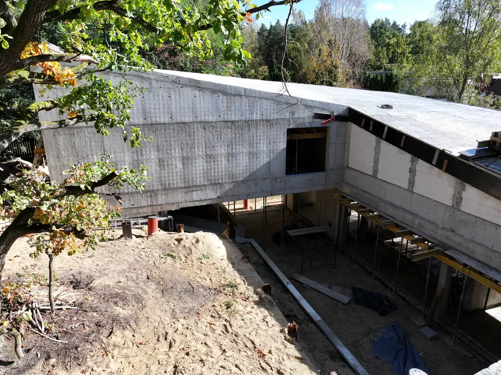 Zbliżenie z drona na stropodach żelbetowego budynku z otworem świetlika lub patio oraz deskowaniem w trakcie prac.