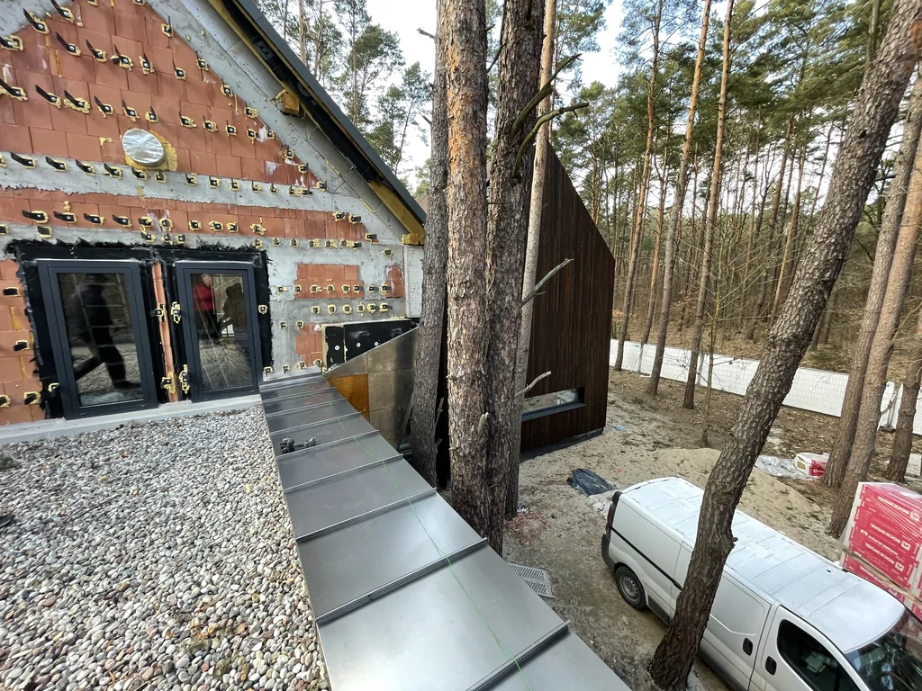 Detal metalowego wykończenia dachu i przejścia przy nowoczesnym domu położonym w lesie