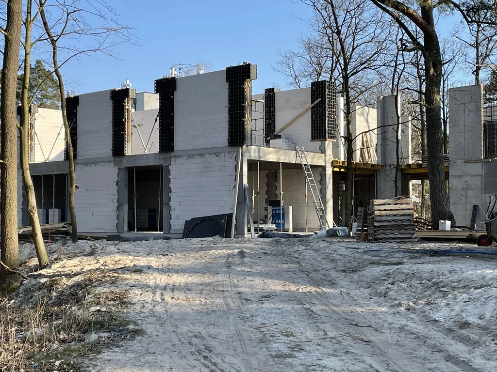 Front budynku w stanie surowym z murowanymi ścianami, żelbetowymi słupami i przygotowaniem pod kolejne kondygnacje