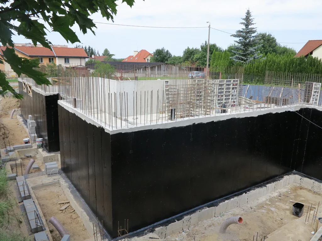 Wylane ściany piwnicy, posmarowane szlamem, widoczne zbrojenei konstrukcji w srodku piwnicy 