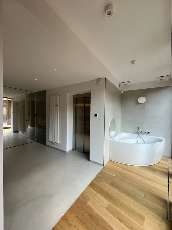 Nowoczesna łazienka z lustrzaną ścianą, wanną narożną i wejściem do strefy prysznica