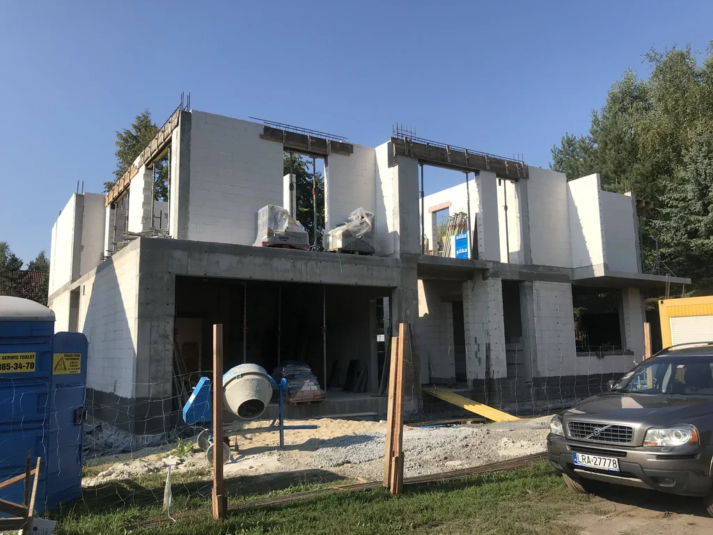 Stan surowy budynku, ściany pustak ceramiczny, w tle betoniarka