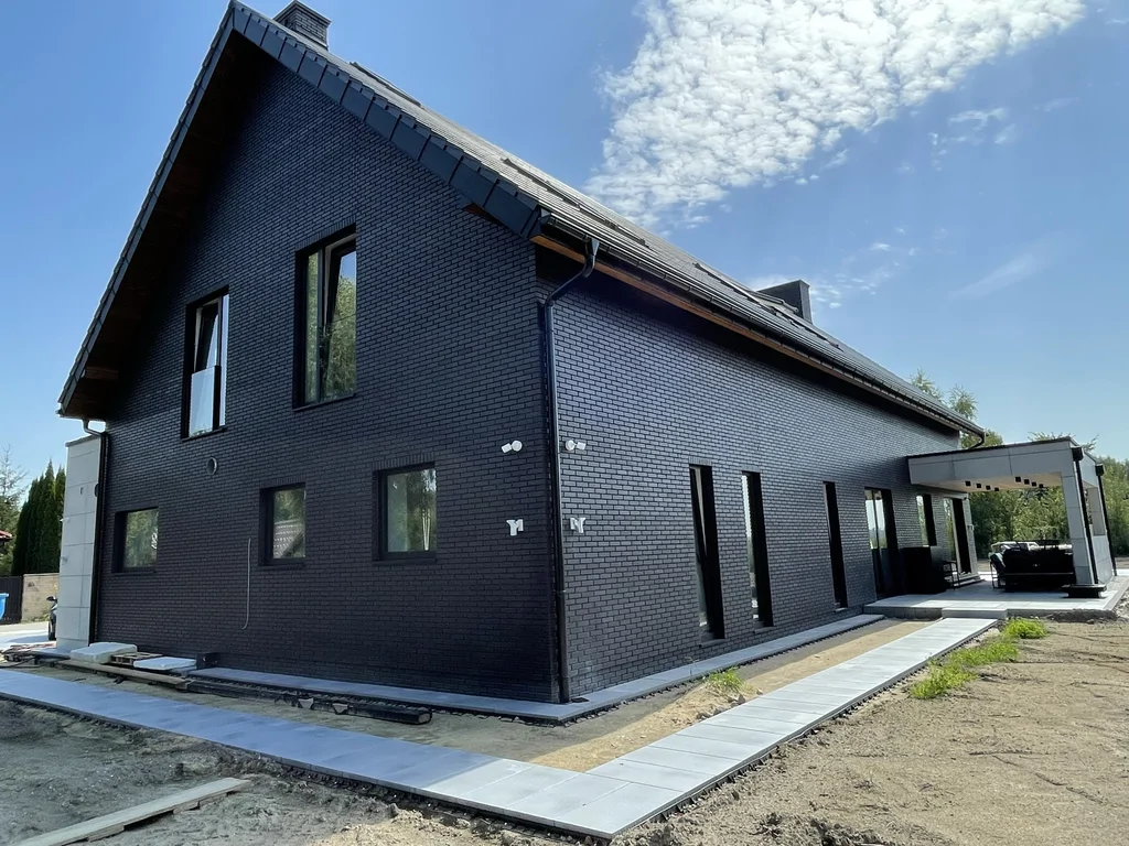 Widok na elewację boczną – czarna cegła, ciąg okien i opaska wokół budynku