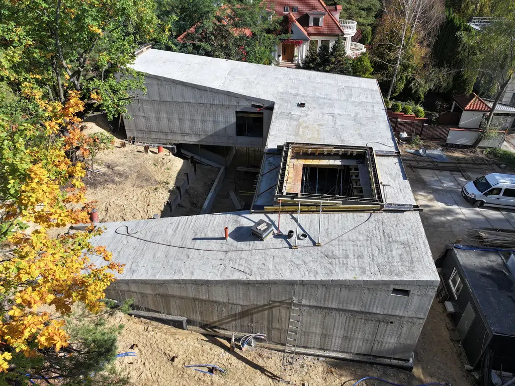 Widok z drona na nowoczesny budynek w stanie surowym z monolityczną konstrukcją żelbetową i wewnętrznym dziedzińcem.