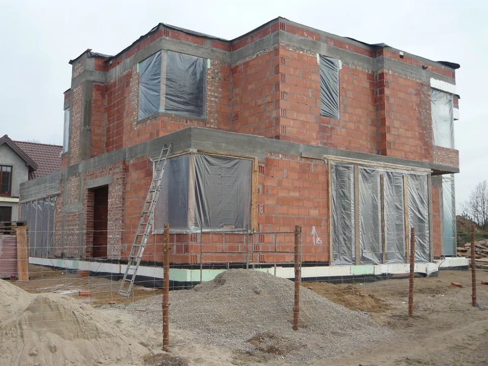 Budynek w stanie surowym z zabezpieczonymi oknami i izolacją na strefie przyziemia
