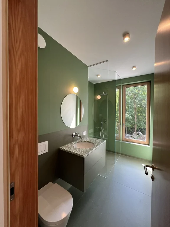 Kabina prysznicowa w zielonej łazience z dużym oknem i widokiem na ogród