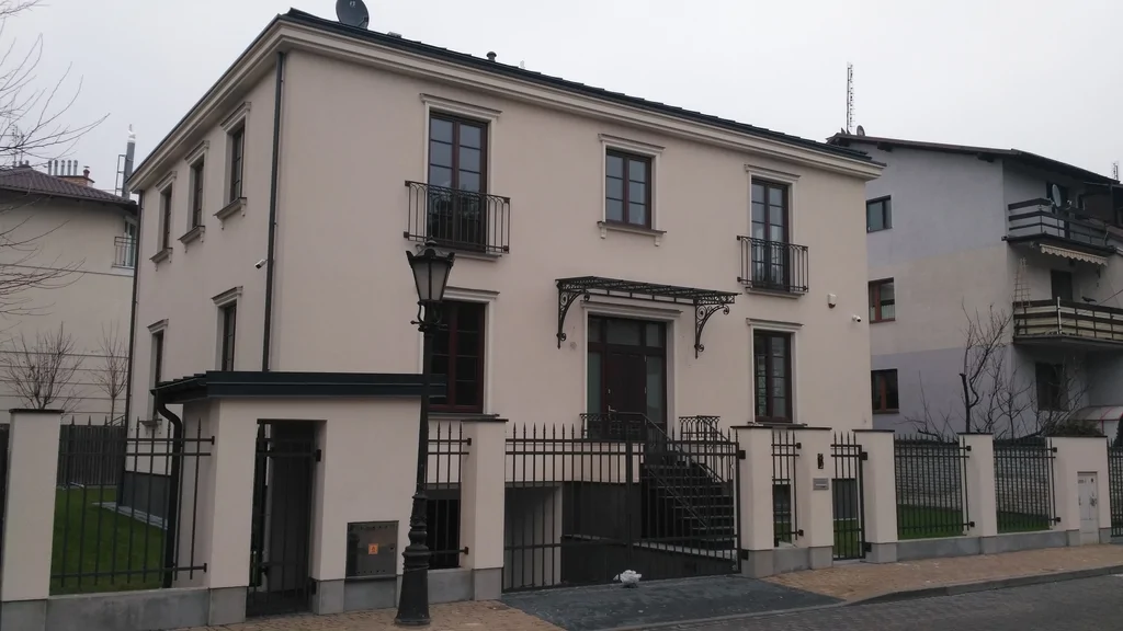 Dom jednorodzinny w stanie deweloperskim, biała elewacja, obróbki stalowe, ciemna stolarka okienna, schody z daszkiem 