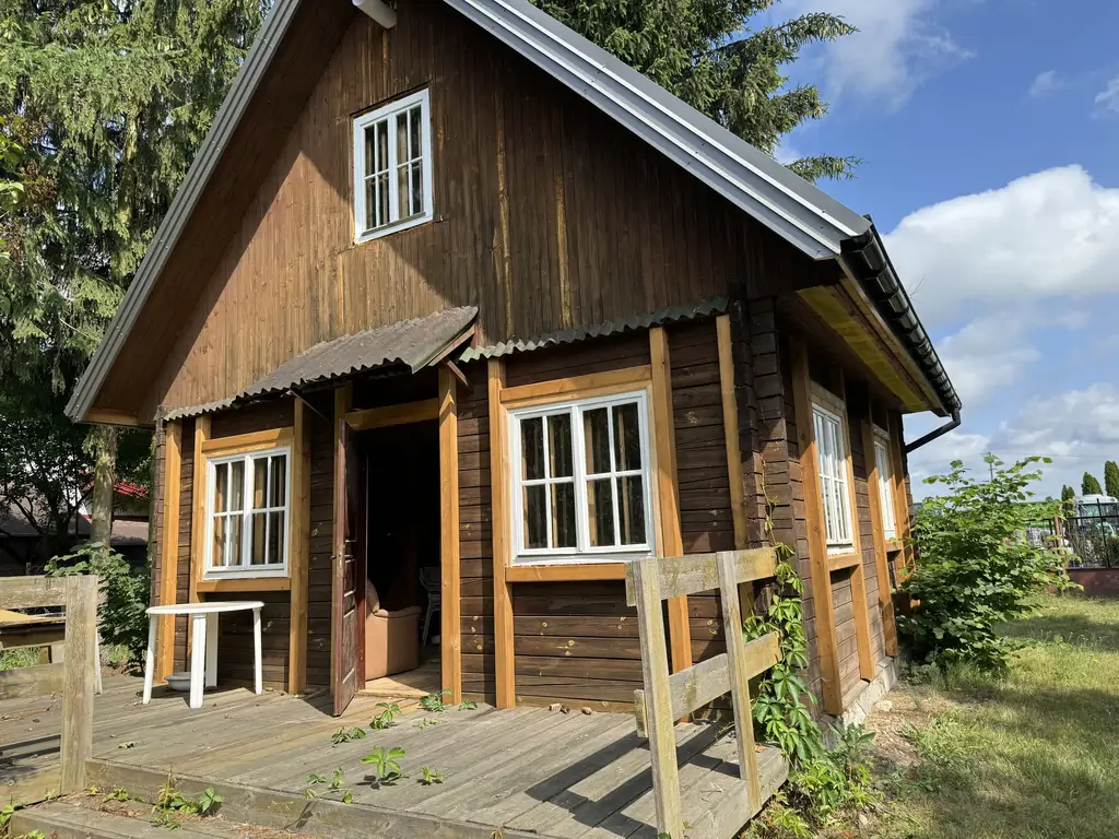 Stary domek drewniany przed renowacją elewacji – widok centralny.