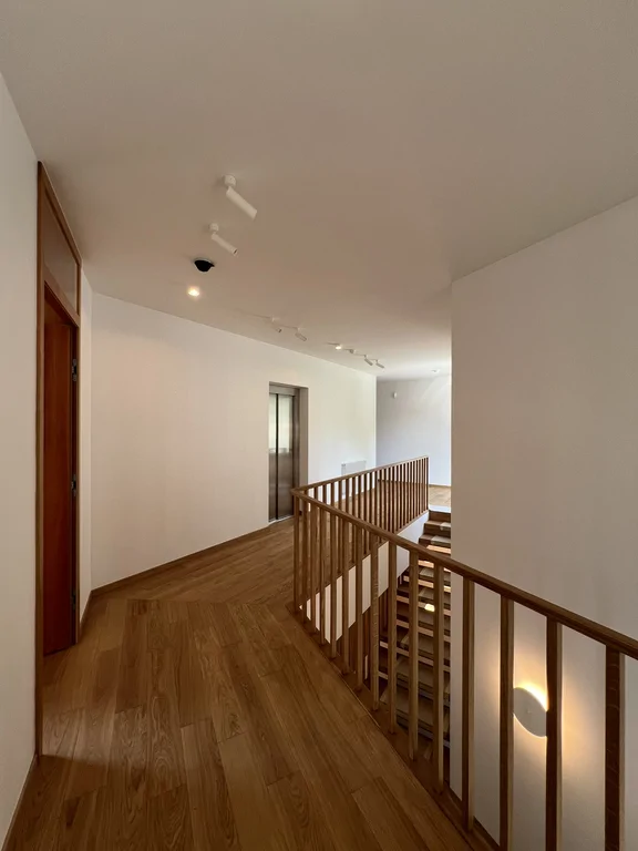 Wąski korytarz z drewnianą podłogą i wysoką zabudową stolarską