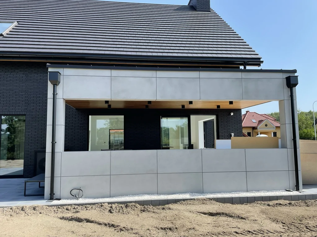 Zadaszony taras – detal okładziny z płyt i podbitki drewnianej z oprawami sufitowymi